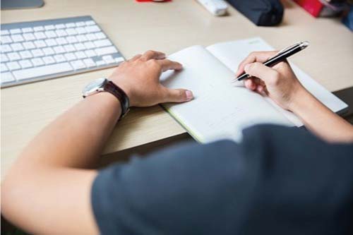 male-student-revising-on-notepad